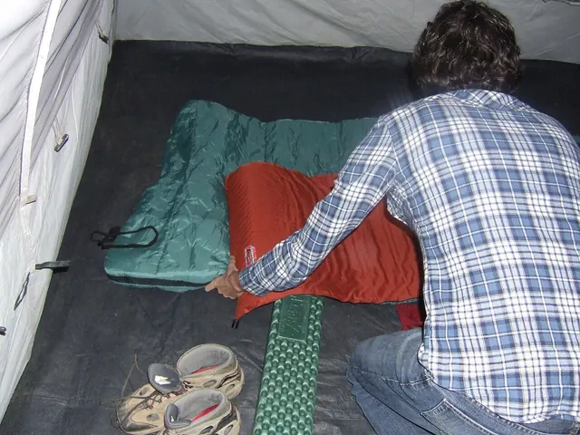 A person adjusting a sleeping bag inside a tent
